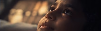 Close-up film still of a child looking upward.